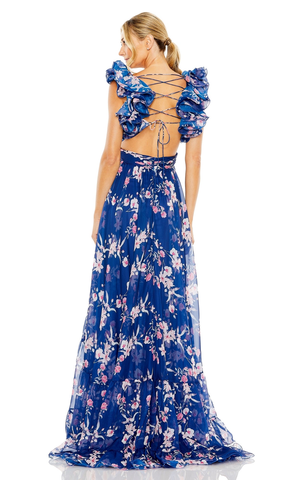 A person stands facing away in a Mac Duggal 68520 long blue print formal dress with ruffled sleeves, lace-up open back, and elegant floral pattern.